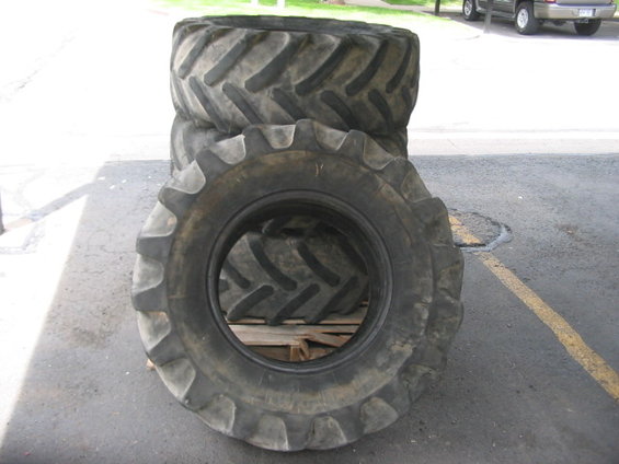 Stack of large tractor tires on a pallet, with one tire in the foreground showing its tread pattern