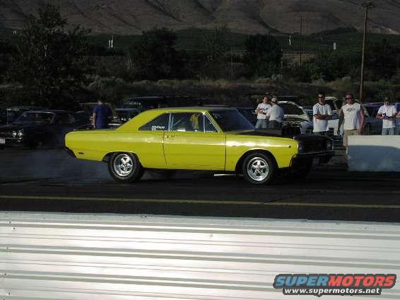 Yellow 1967 Dodge Dart muscle car, side view, black hood, drag strip
