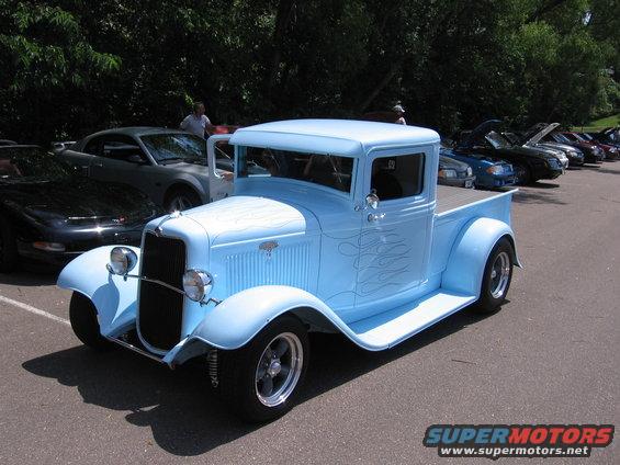 Light blue hot rod pickup truck with flame decals, front 3/4 view