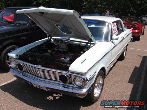 1962 Ford Falcon with hood open, showing engine and scoop. Black truck and red convertible in background