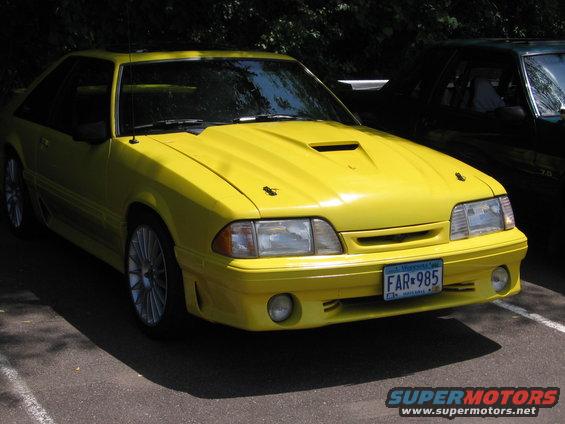 Yellow 1989 Ford Mustang parked next to a dark car