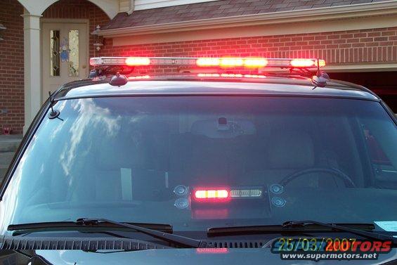 Front view of a police car with a light bar and red lights illuminated