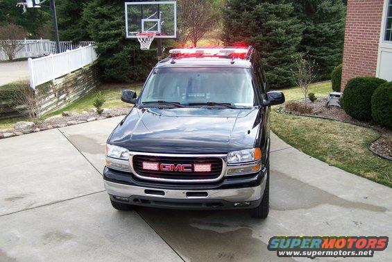 Black GMC SUV with light bar on roof and GMC logo on grille, parked in driveway