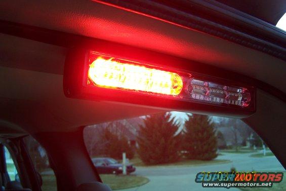 overhead light bar with red and yellow LEDs, view out window shows a dark sedan