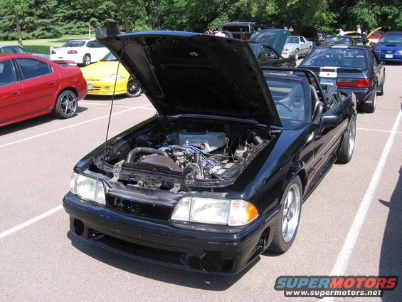 Black 1989 Ford Mustang convertible with hood open, parked in lot with other cars