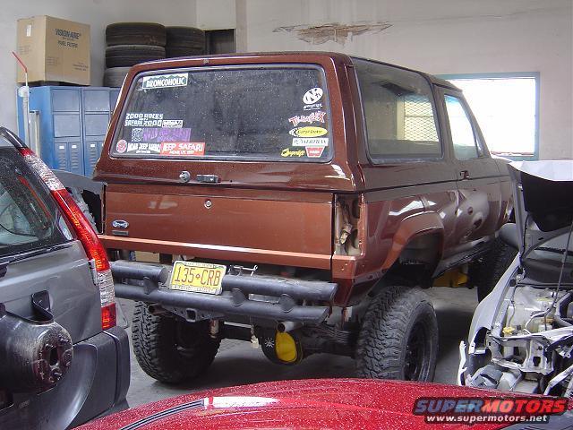 Brown Ford Bronco II with aftermarket bumper and yellow differential cover, viewed from rear