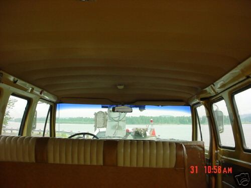 Interior view of a van showing tan seats and a dashboard with a lake in the background