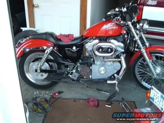 Red Harley-Davidson motorcycle parked in a garage with tools on the floor