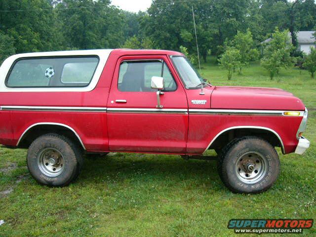 1978 Ford Bronco, red with white top, parked on grass