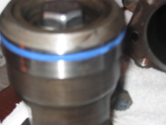 Metal cylinder with a blue ring and a hex bolt on top