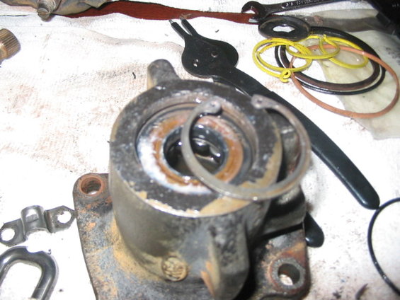 Disassembled hydroboost cylinder with snap rings and assorted O-rings and tools on a white cloth