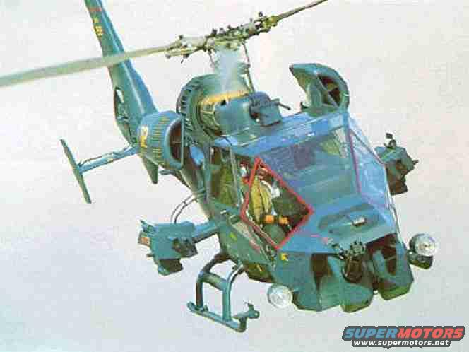 Attack helicopter in flight, front 3/4 view. Pilot visible in cockpit