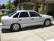1995 Ford Taurus - A white sedan is parked in a driveway with a house and garage in the background.