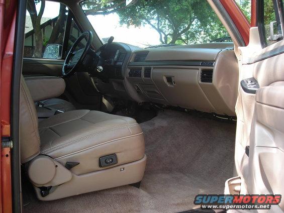 Interior of a tan truck, showing the driver's seat, dashboard, and passenger side door