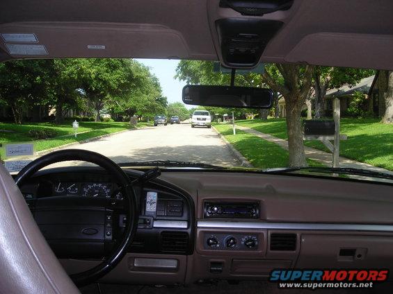 Interior view from driver's seat looking down a suburban street with a white van and other cars ahead