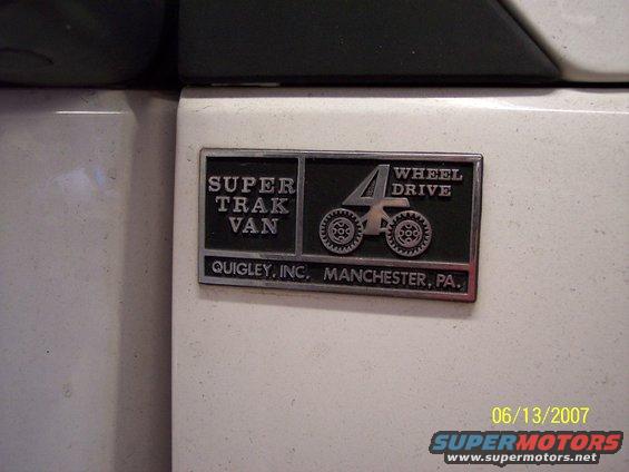 Close-up of a "Super Trak Van 4 Wheel Drive" badge from Quigley Inc. in Manchester, PA
