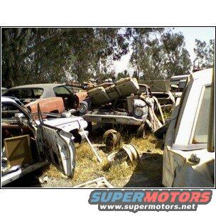 Junked car parts in a yard, SuperMotors.net logo visible