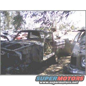 Car chassis with open door, stripped interior, and damaged front end in a junkyard