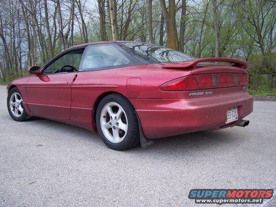 Red Ford Probe parked on asphalt with trees in background. Rear spoiler and 'PROBE 24V' badge visible