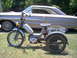 1963 Ford Ranchero - A three-wheeled moped sits in front of a classic car, possibly a 1963 Ford Ranchero.