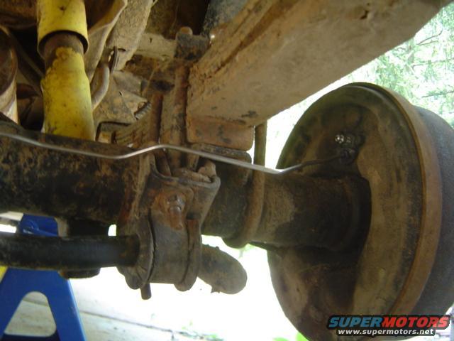 Rusty rear axle assembly with yellow shock absorber and brake drum