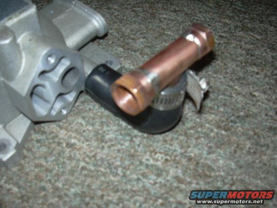 Metal automotive part with copper pipe and hose clamp on carpet