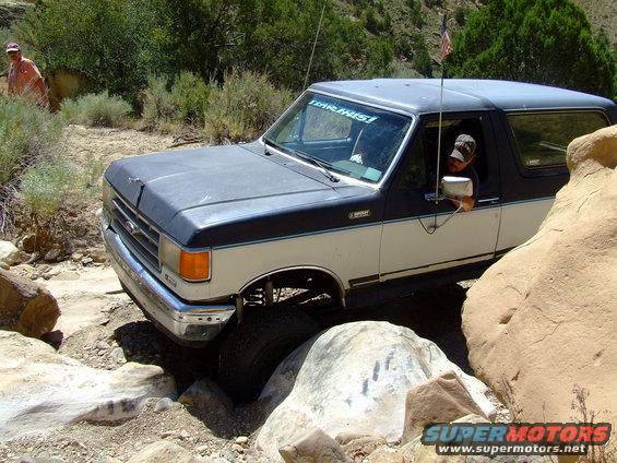 1987 Ford Bronco navigating a rocky trail, driver visible