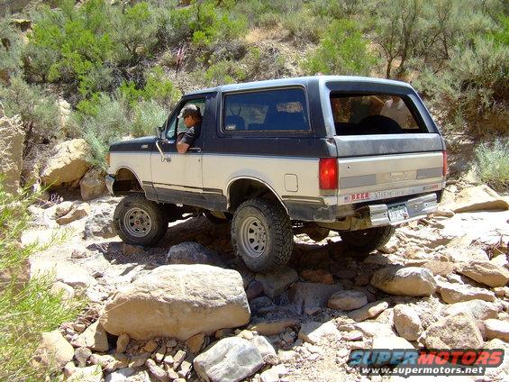 Two-tone 1987 Ford Bronco navigating a rocky trail