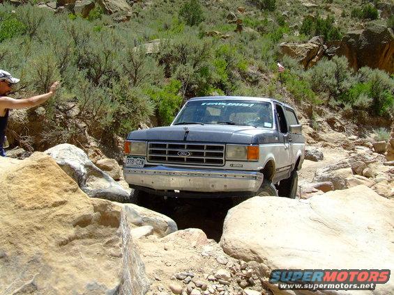 Two-tone gray and white Ford Bronco navigating rocky terrain