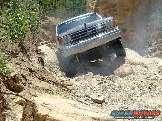 Silver 1987 Ford Bronco navigating a rocky off-road trail