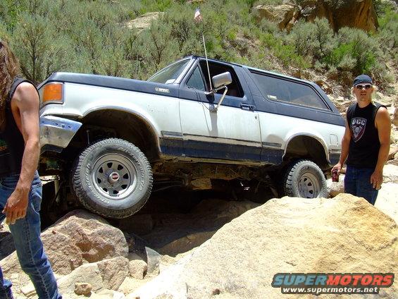 White and blue 1987 Ford Bronco navigating rocky terrain