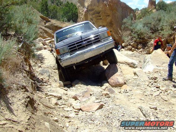 Ford truck navigating a rocky trail, front grille visible