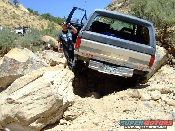 1987 Ford Bronco navigating a rocky trail with a person drinking from a can