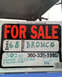 1973 Ford Bronco - Sign advertises a 1968 Bronco for sale, listing features like 302 GT and power steering, with a contact number provided.