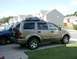 2004 Dodge Durango - A gold 2004 Dodge Durango is parked in a driveway next to a blue truck, with houses in the background.