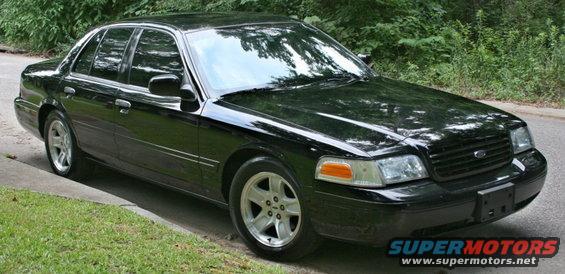 Black 2002 Ford Crown Victoria parked on a grassy shoulder, front 3/4 view