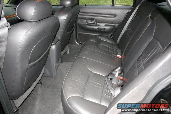 Back seats and door panel of a car. Black leather seats with seatbelts