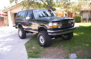 Dark green Ford Bronco parked in driveway, front quarter view