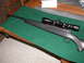 1991 Ford Bronco - A rifle with a scope is displayed on a green felt mat on a wooden table.