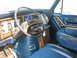 1978 Ford E250 - The interior of a vintage Ford van features blue upholstery, wood-grain trim, and a dashboard with gauges.