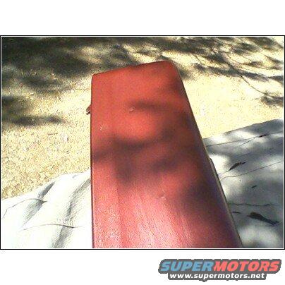 Red car part, possibly a fender or hood section, outdoors