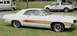 1976 Ford Ranchero - A white convertible muscle car is parked on grass with a pickup truck and RV in the background.