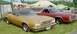 1976 Ford Ranchero - A gold 1973 Ford Ranchero is parked next to a red Ranchero and other vehicles at an outdoor event.