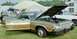 1976 Ford Ranchero - A green pickup truck with wood paneling is displayed with its hood and door open at an outdoor event.