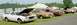 1976 Ford Ranchero - A line of classic cars, including a white 1976 Ford Ranchero, are parked on a grassy field under tents.