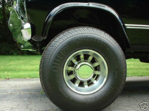 Black 1978 Ford E250 side view showing chrome bumper, fender flare, and alloy wheel with a "GIANT" tire