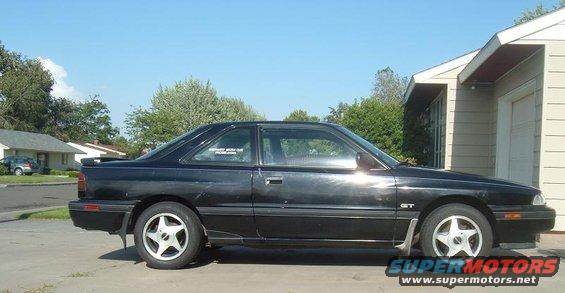 Black coupe parked in front of a house. It has a 'GT' badge on the fender