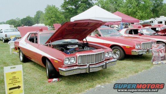 Red 1976 Ford Ranchero with white stripe and hood open, parked on grass