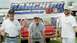 1976 Ford Ranchero - Three men pose for a photo while holding a banner at an outdoor event.