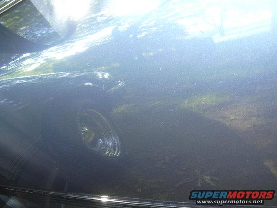 Dark blue car side view with reflections. Chrome trim visible